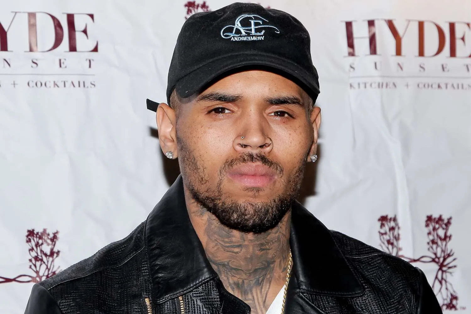 Chris Brown in a black cap and leather jacket at an event