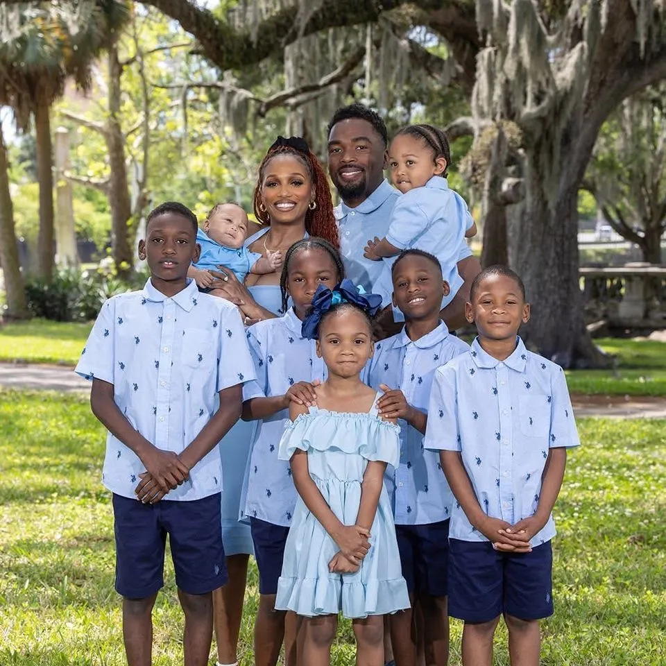 Shantel Patrice Ennis with her fiancé and children in matching blue outfits under oak trees