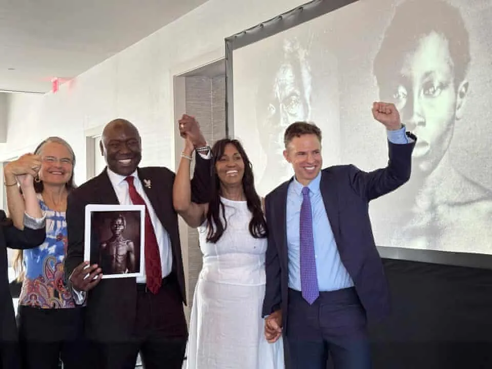 Descendants and supporters raise their fists at a press conference in front of a projected 1850 daguerreotype
